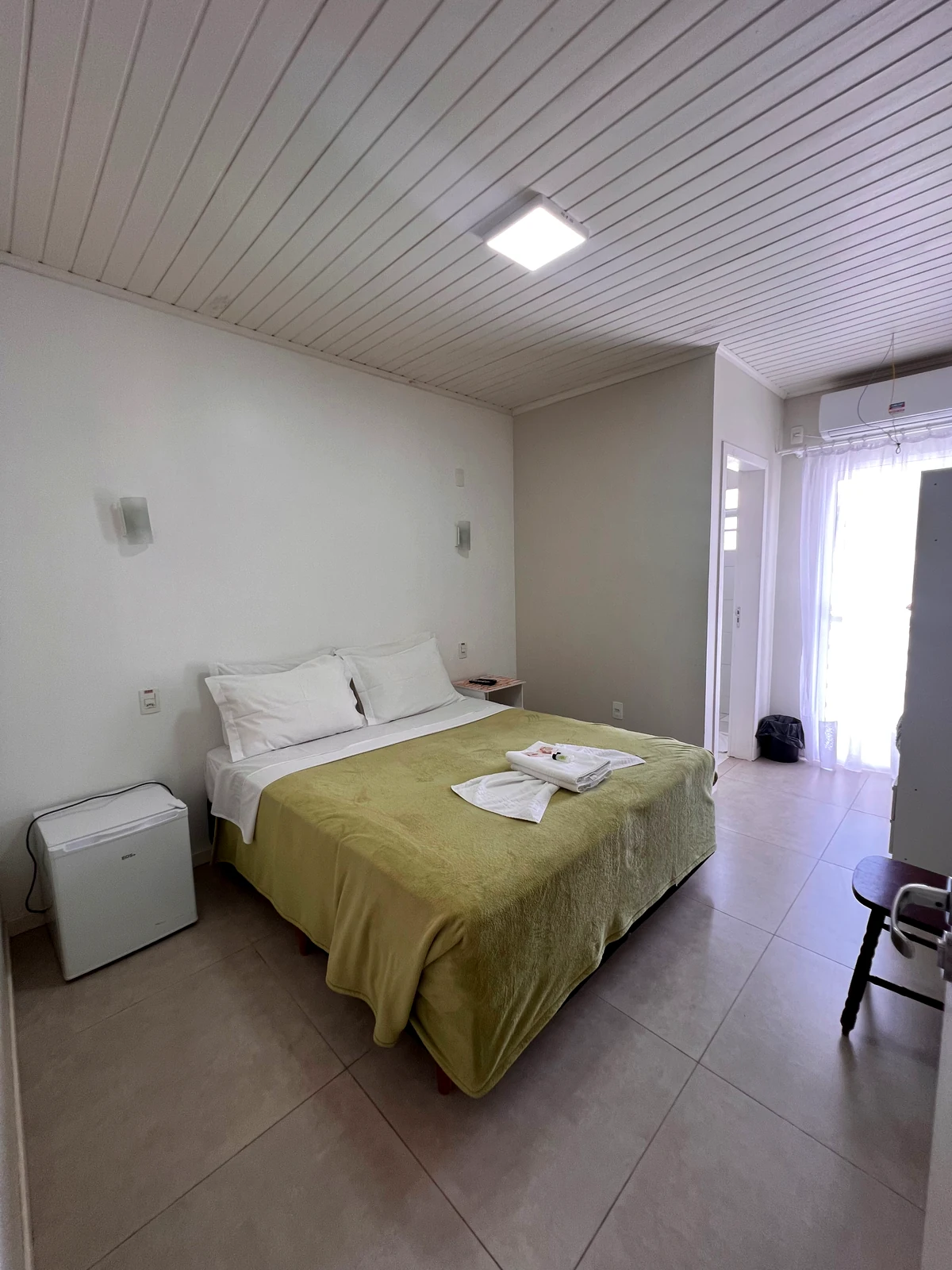 Quarto pousada UpSerra com colcha verde
